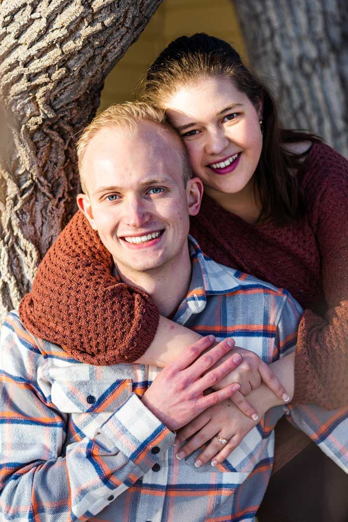 Couple posing next to a tree